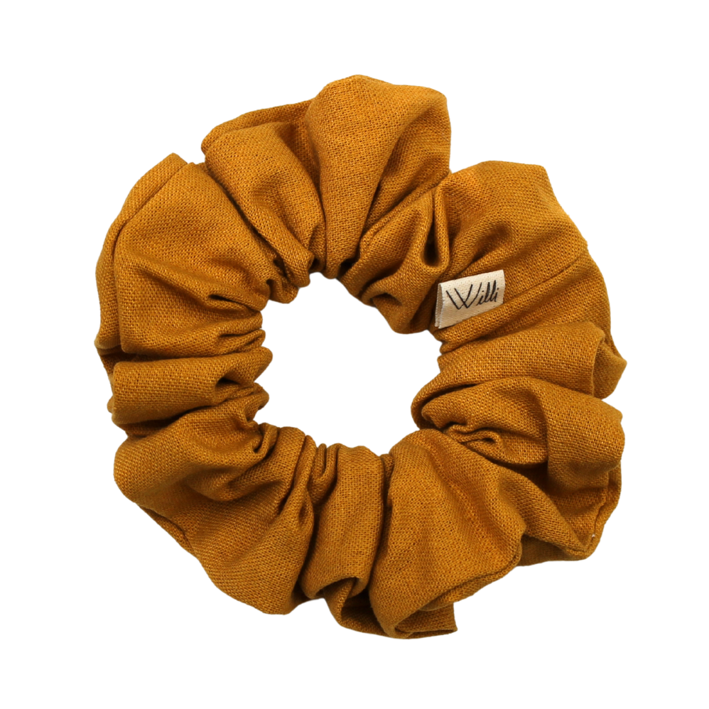 Mustard yellow scrunchie with a brand label on a white background