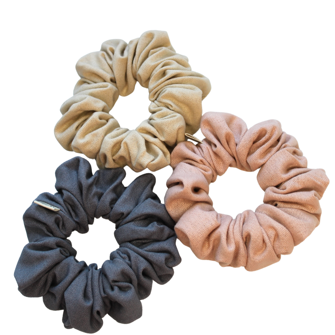 Three scrunchies in beige, gray, and pink on a white background