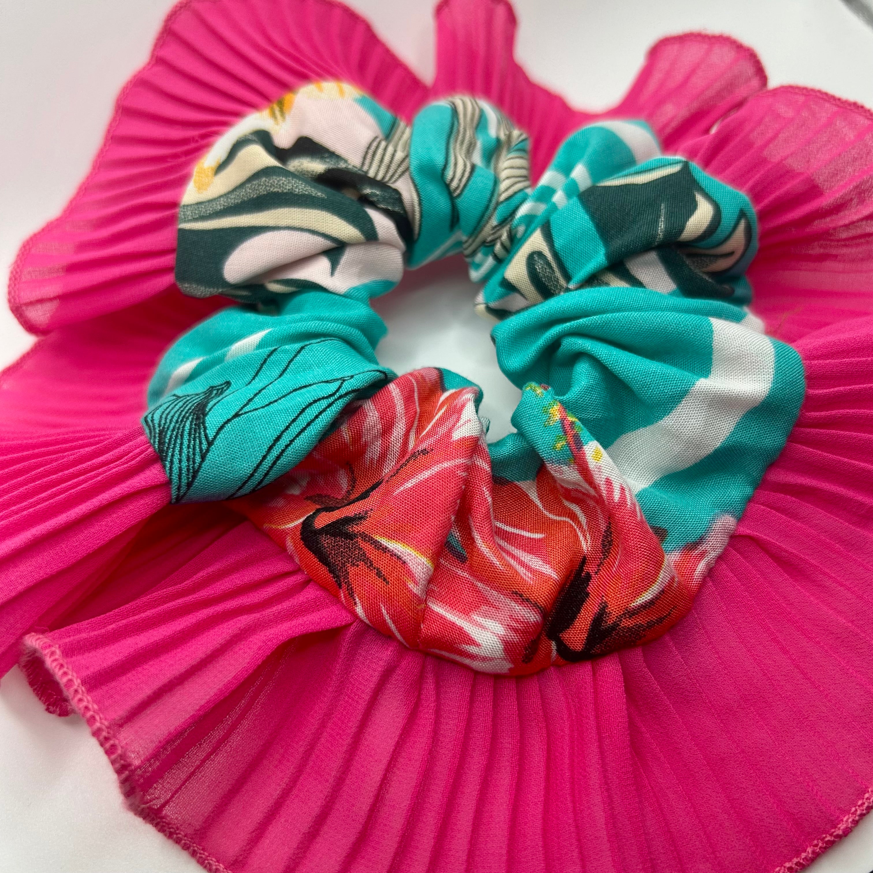 Teal scrunchies on a pink pleated fabric background