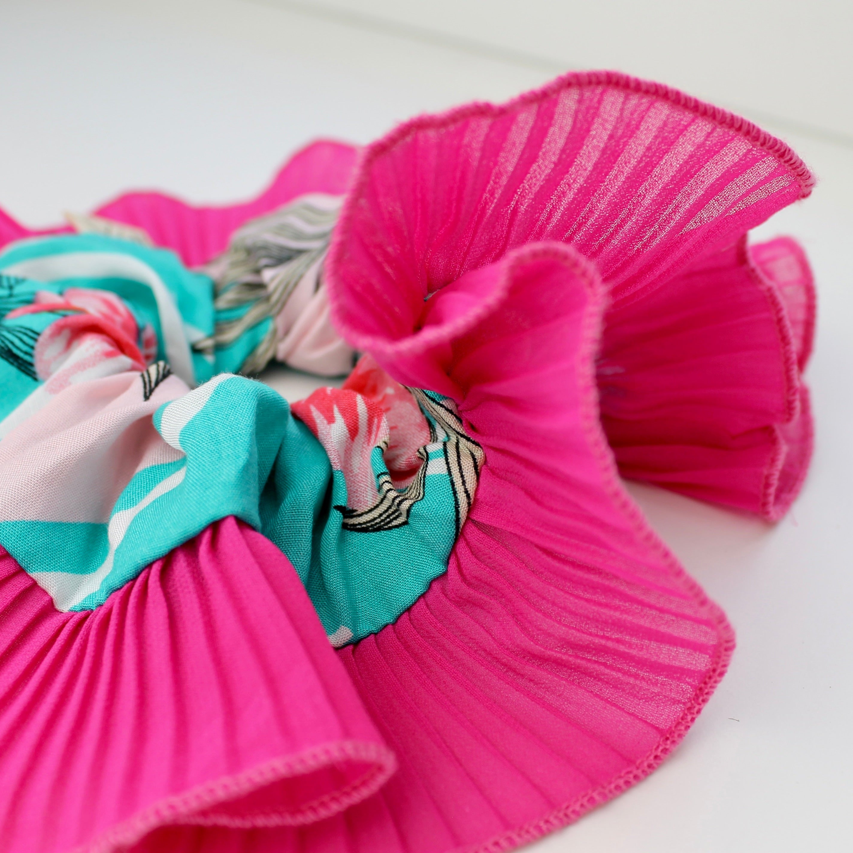 Pink hair scrunchies with colorful designs on a white background
