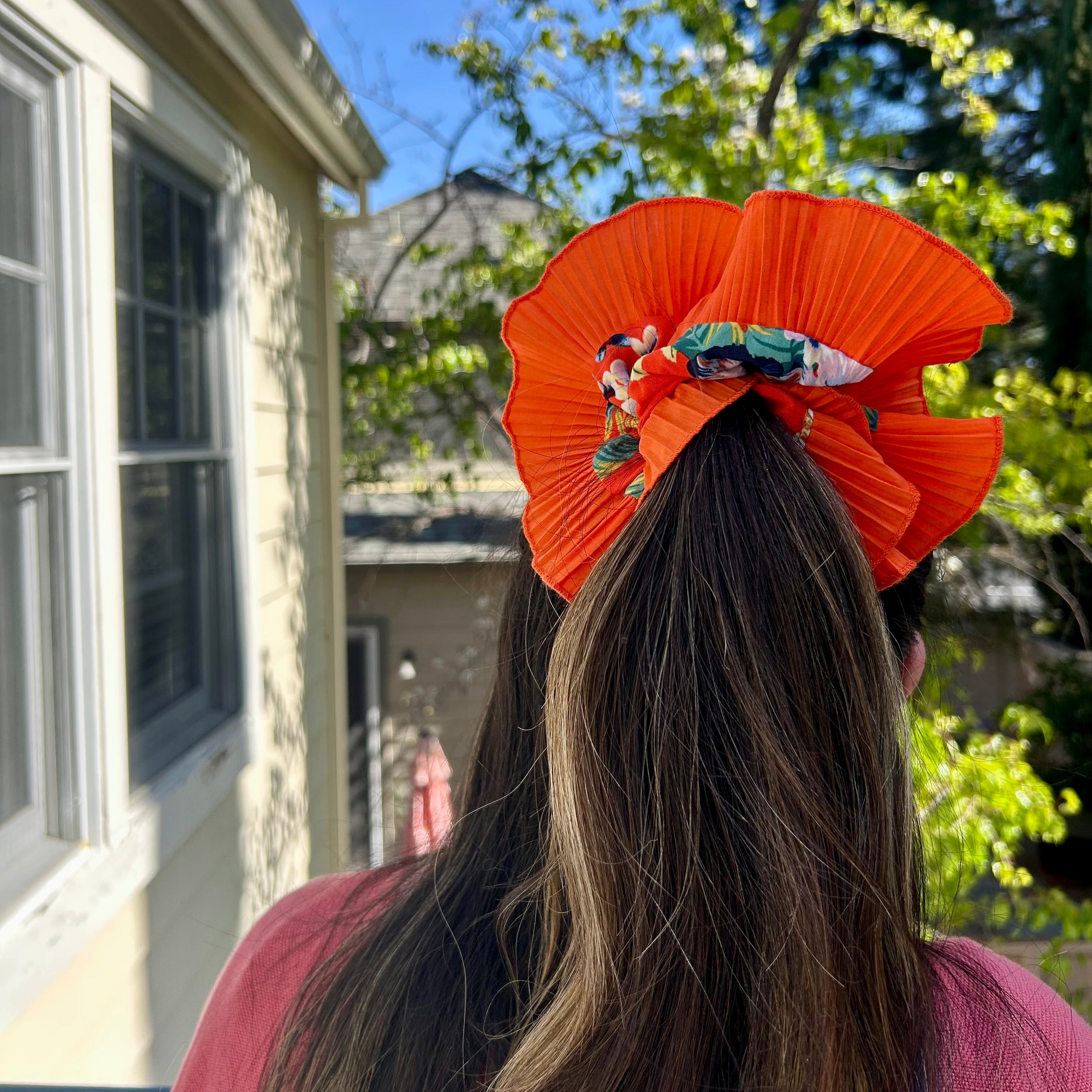 Person wearing an orange hair tie with flowers outdoors