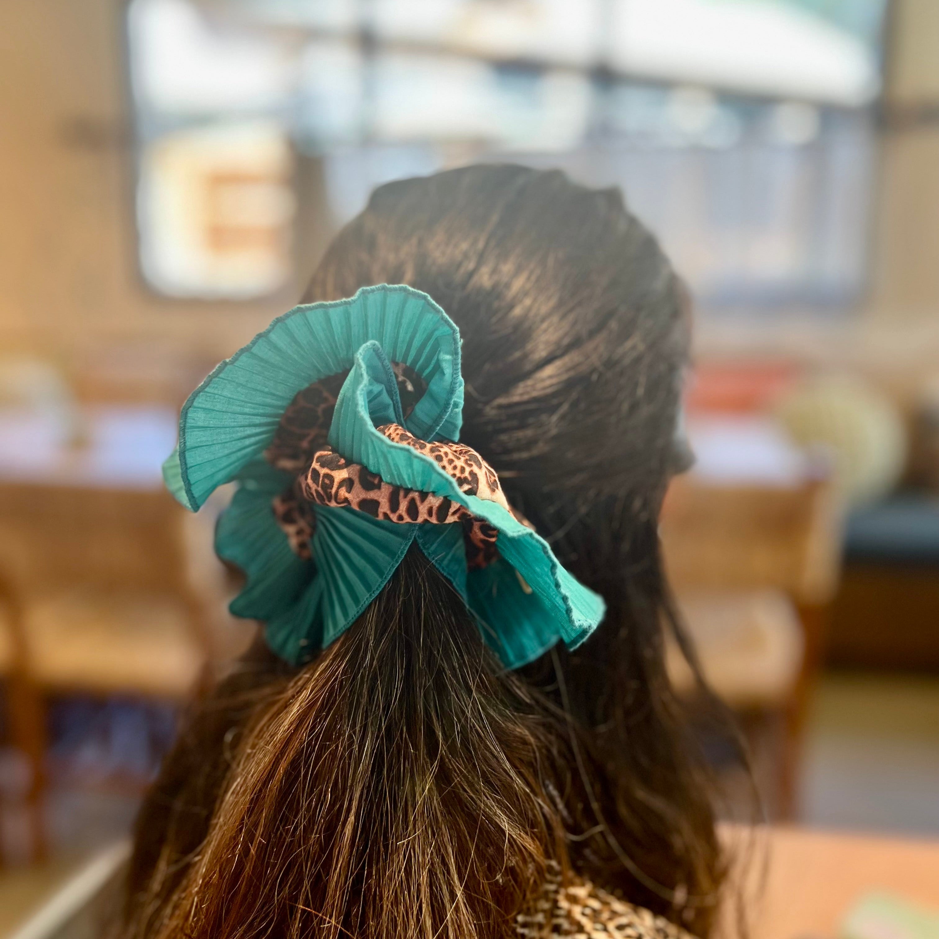 Person with teal hair accessory in a blurred indoor setting