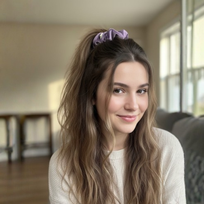 Woman with long brown hair and a purple scrunchie in a living room setting