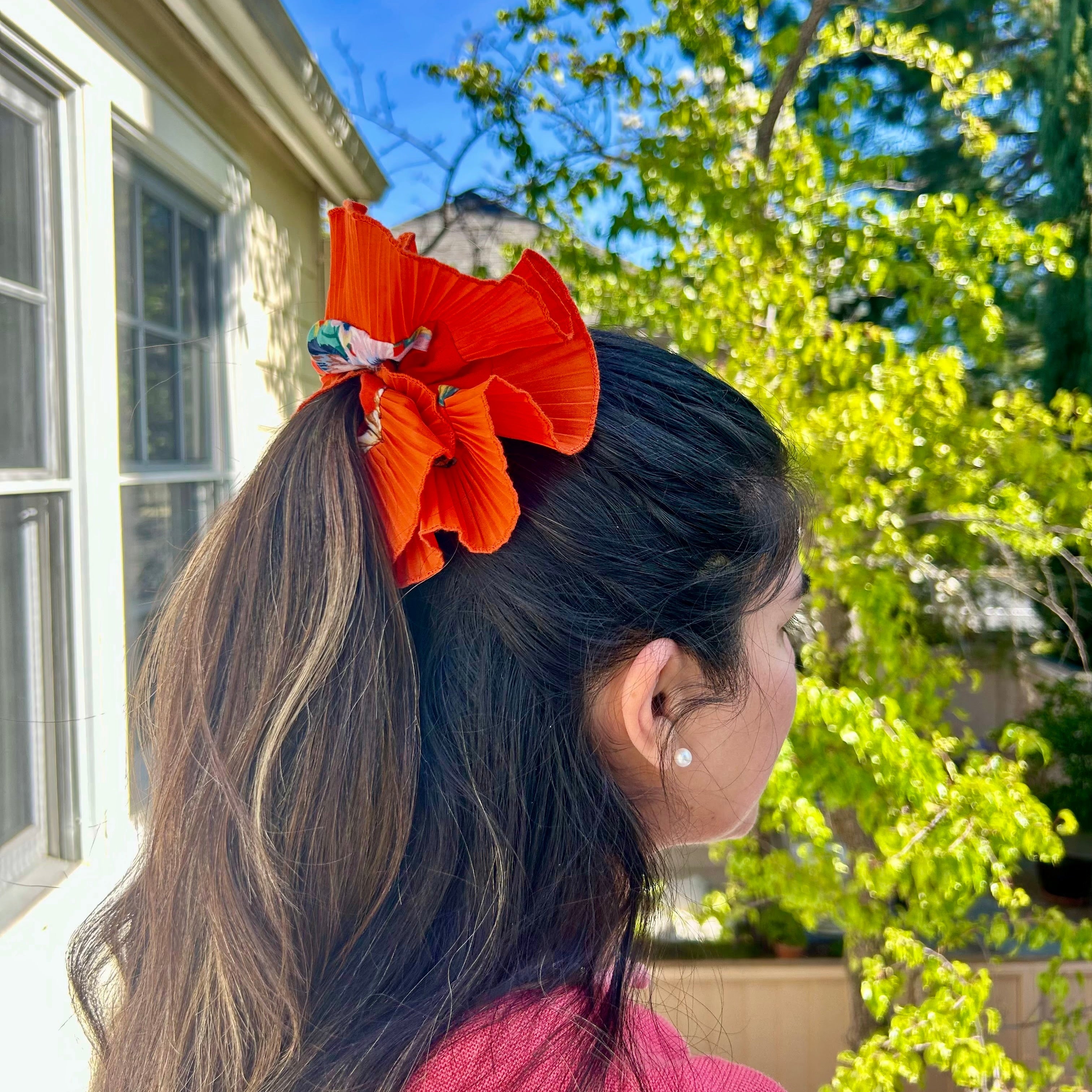 Person with orange scrunchie in hair outdoors