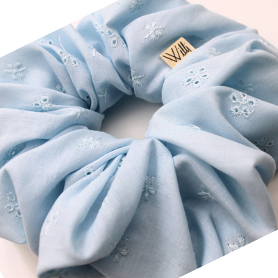 Light blue scrunchie with floral embroidery on a white background