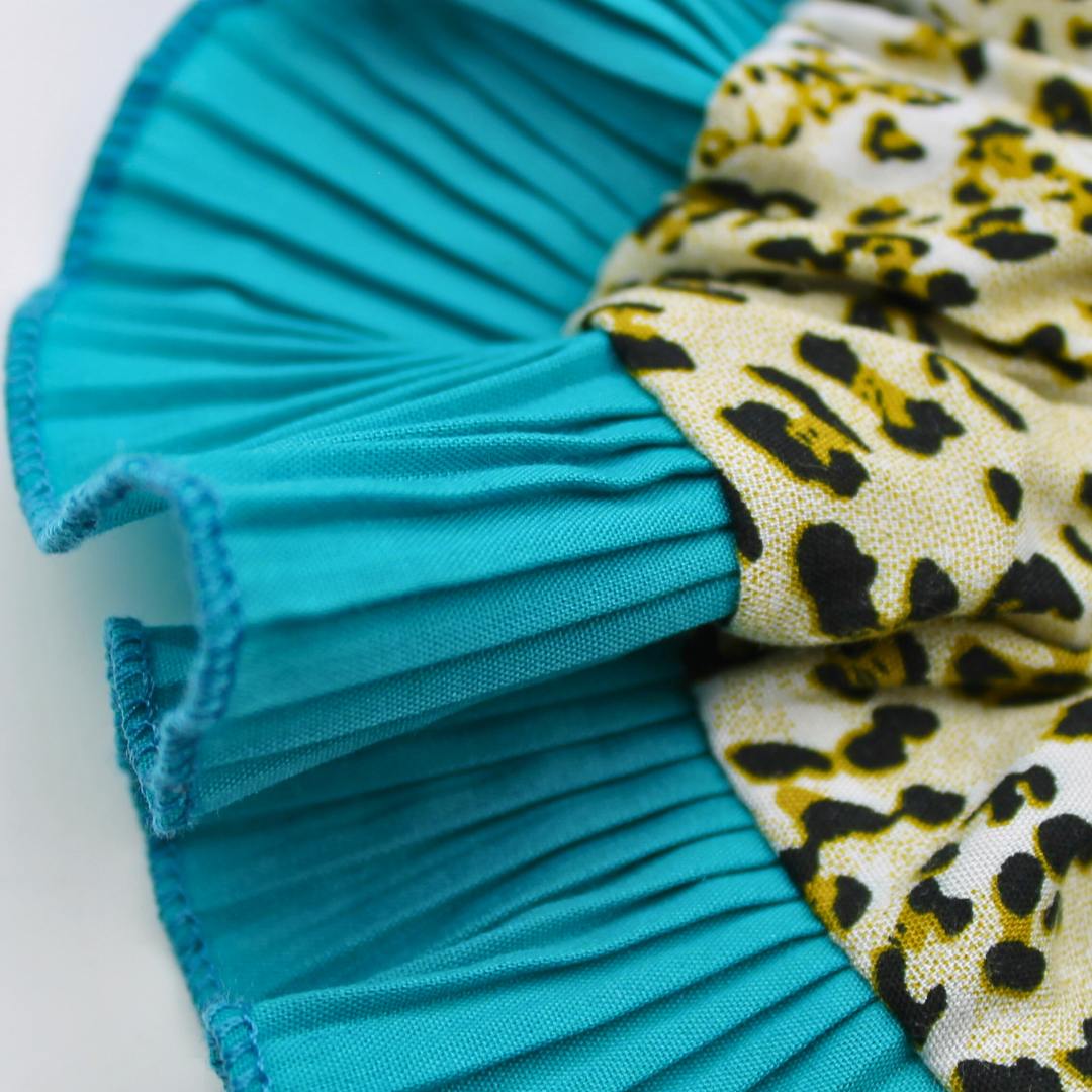 Close-up of turquoise pleated fabric and leopard print fabric on a white background