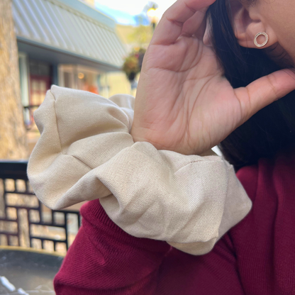 Person wearing a beige scrunchie in her arm outdoors