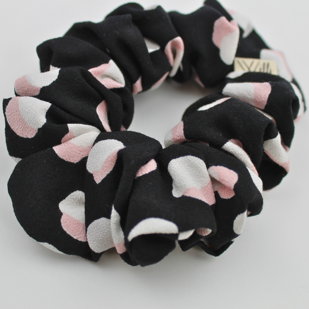 Black scrunchie with pink and white circules patterns on a light gray background