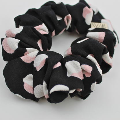 Black scrunchie with pink and white circules patterns on a light gray background