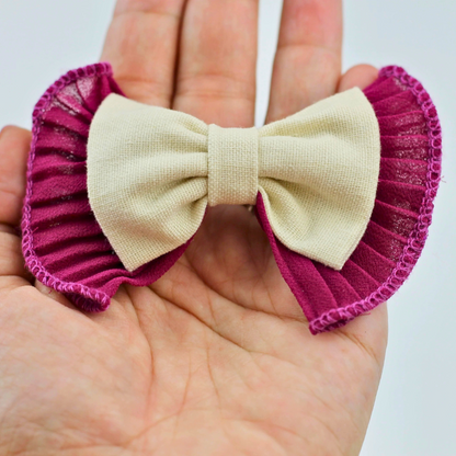Beige bow with pink ribbons held in a hand against a white background