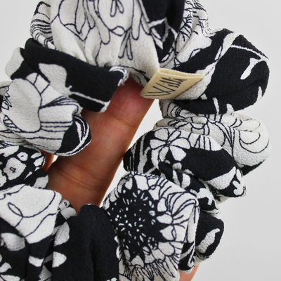 Black and white patterned scrunchies on a hand against a light background