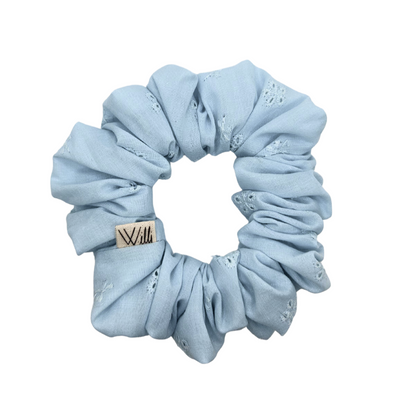 Light blue scrunchie with a brand tag on a white background
