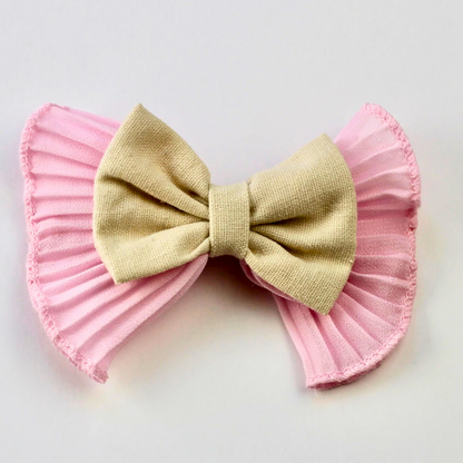 Bow-shaped hair accessory with pink ruffled layers on a white background