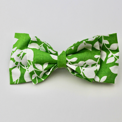 Green bow tie with white floral pattern on a light gray background