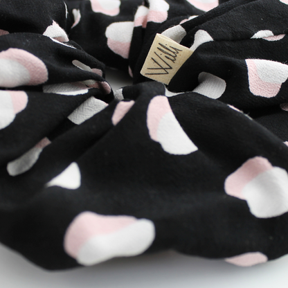 Black scrunchie with pink paw prints and a visible brand tag on a white background