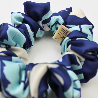 Navy and light blue patterned scrunchie with a brand tag on a white background