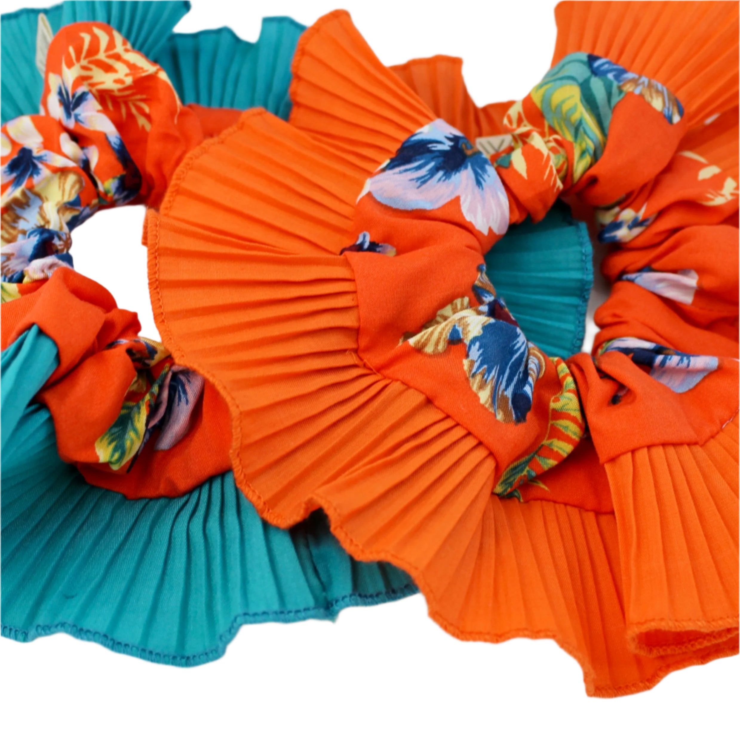 Two colorful scrunchies, one orange and one teal, with floral patterns on a white background.
