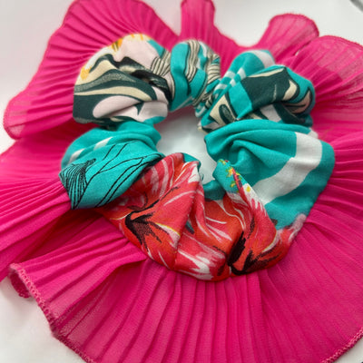 Teal scrunchies on a pink pleated fabric background