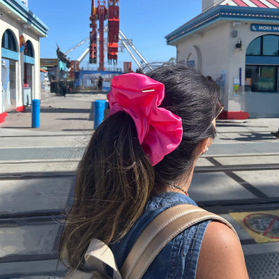Woman from behind with a big pink satin scrunchie 
