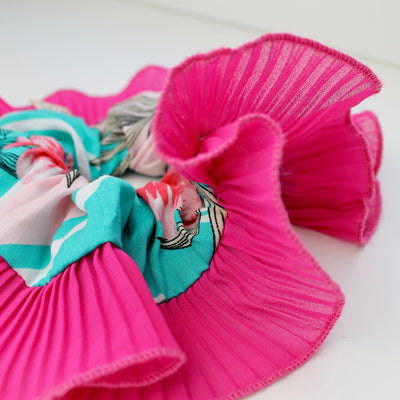Pink hair scrunchies with colorful designs on a white background
