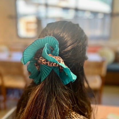 Person with teal hair accessory in a blurred indoor setting