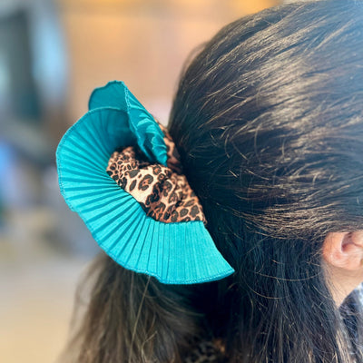 Turquoise scrunchie with leopard print detail on a person's hair