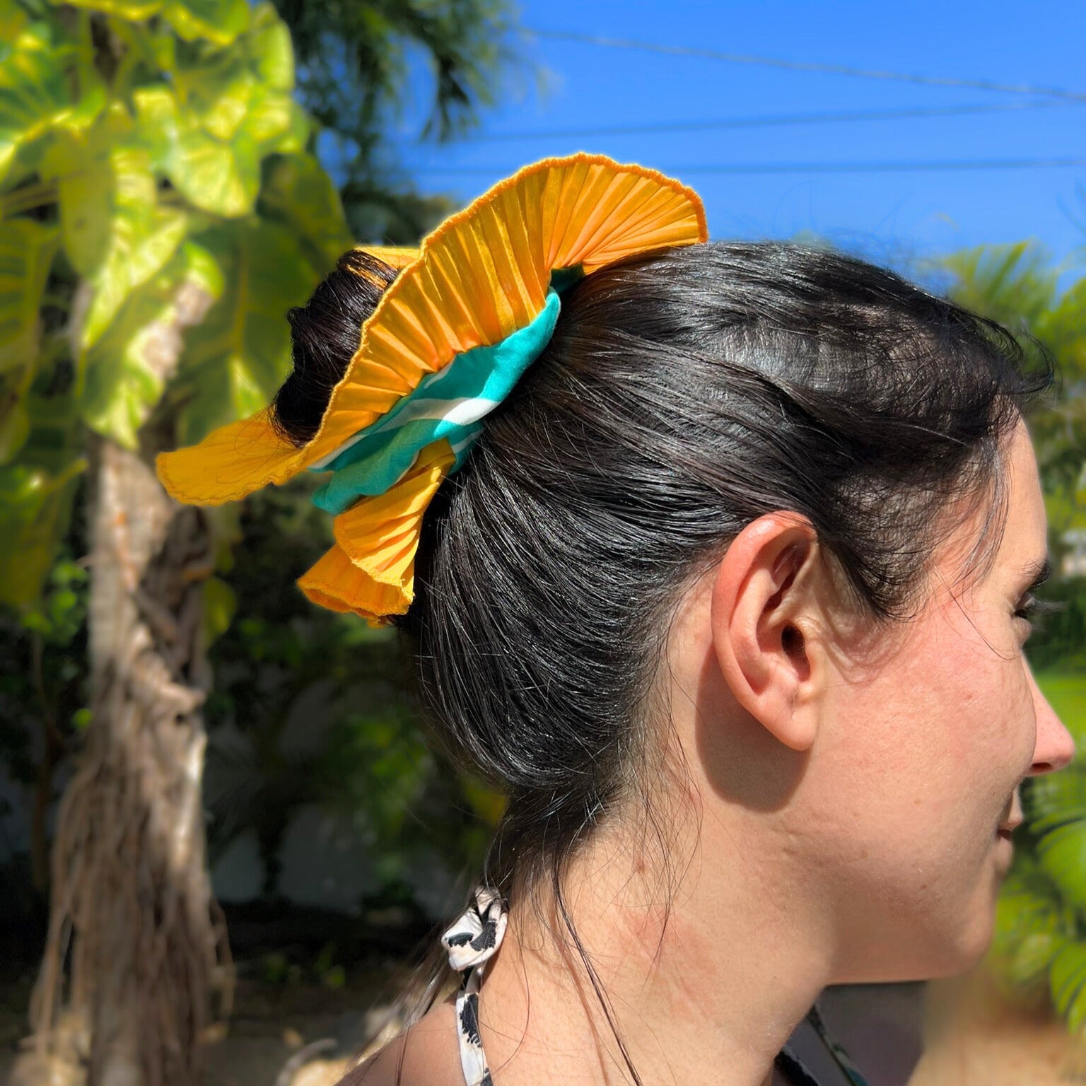 Woman with a yellow and green floral hair accessory outdoors