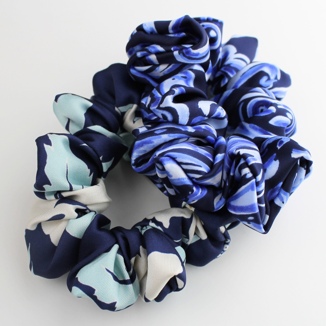 Set of blue and white patterned scrunchies on a light gray background