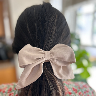 Person with a large pink bow in their hair, wearing on a floral dress.